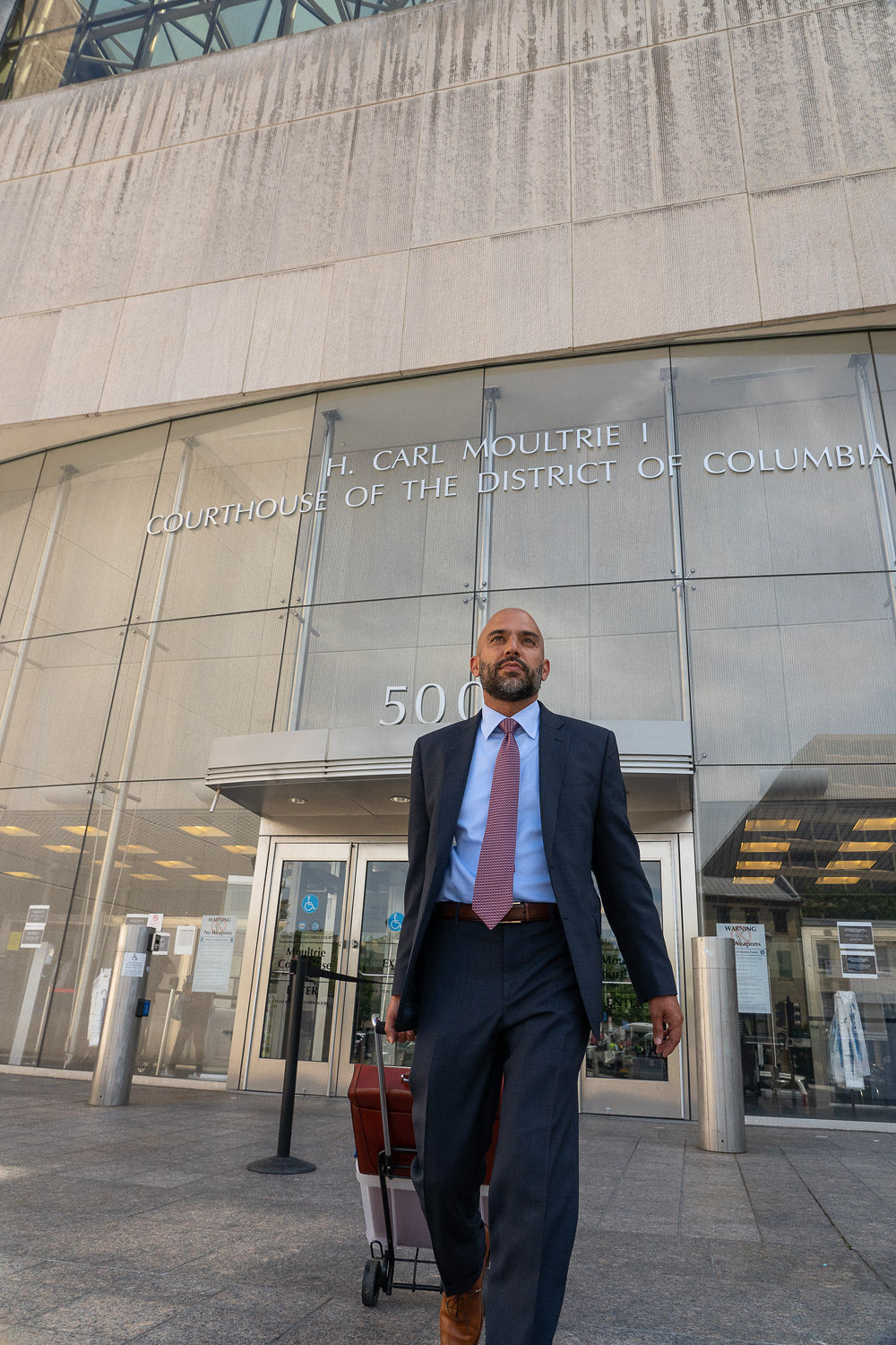 Lawyer walking out of the courthouse with a trial cart.